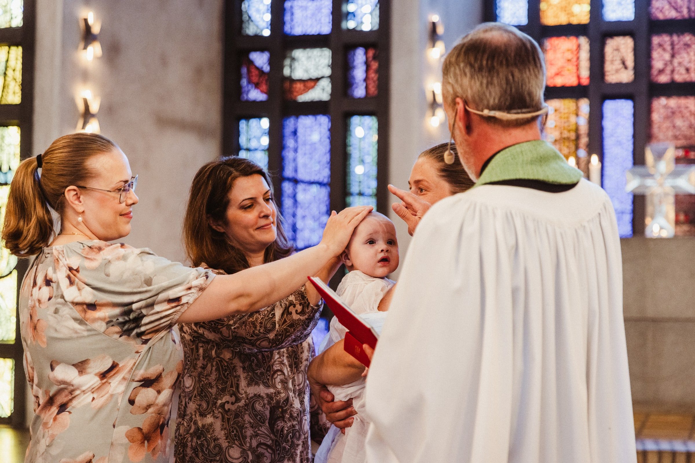 Family gathered around a baby during a baptism blessing.