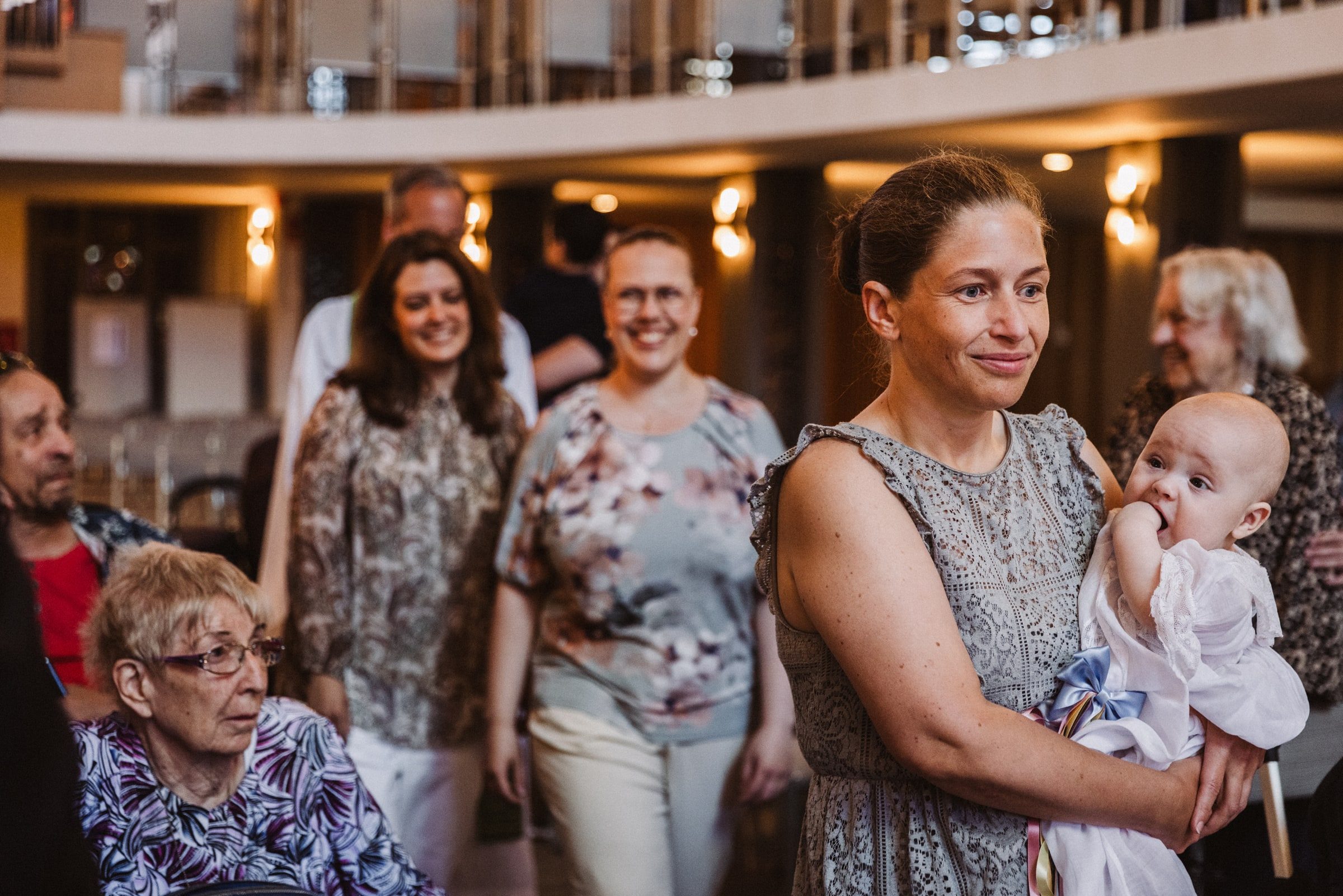 Mother holding her baby as family members gather inside the church.
