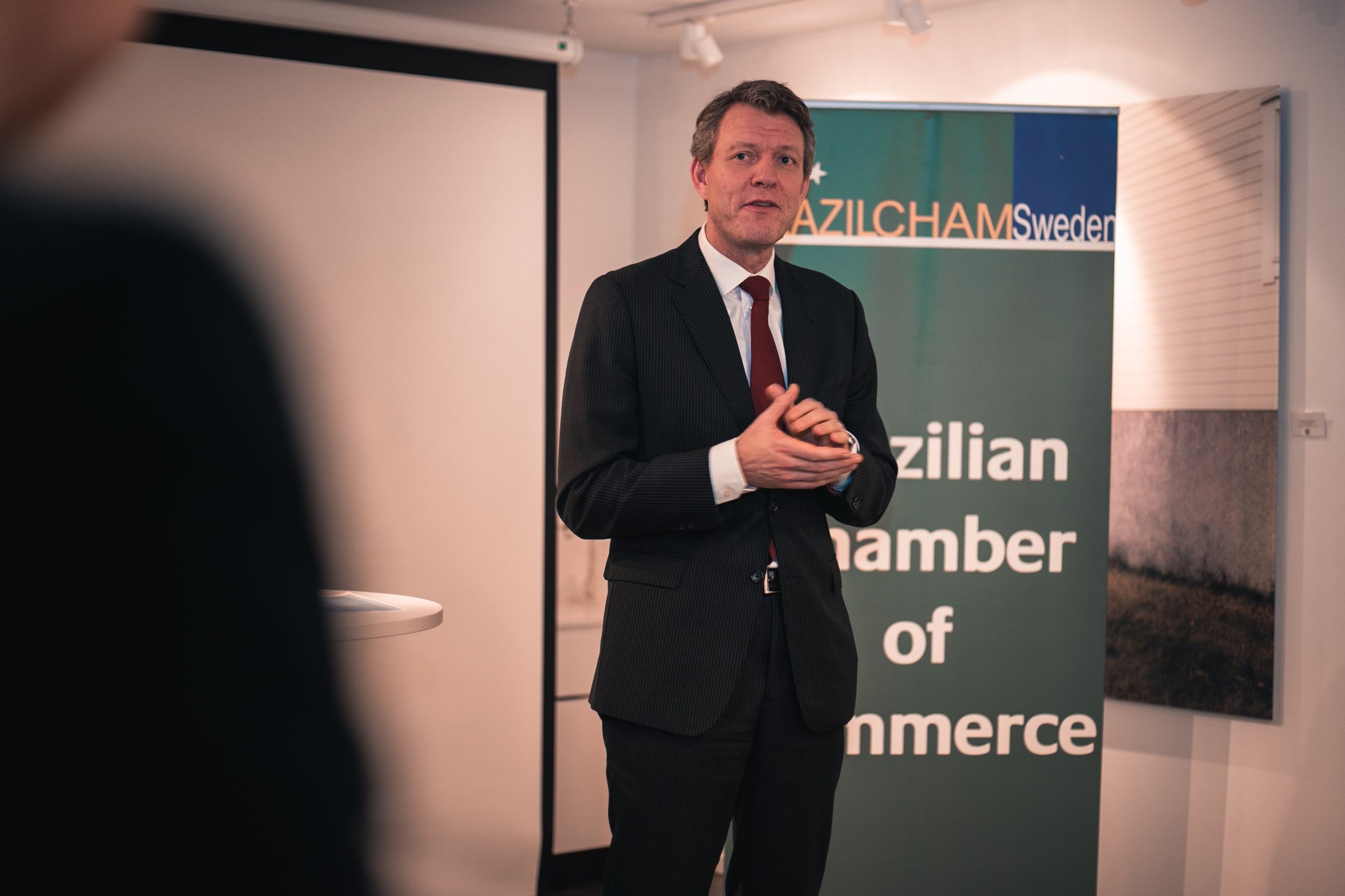 Man addressing reception guests beside the event banner.
