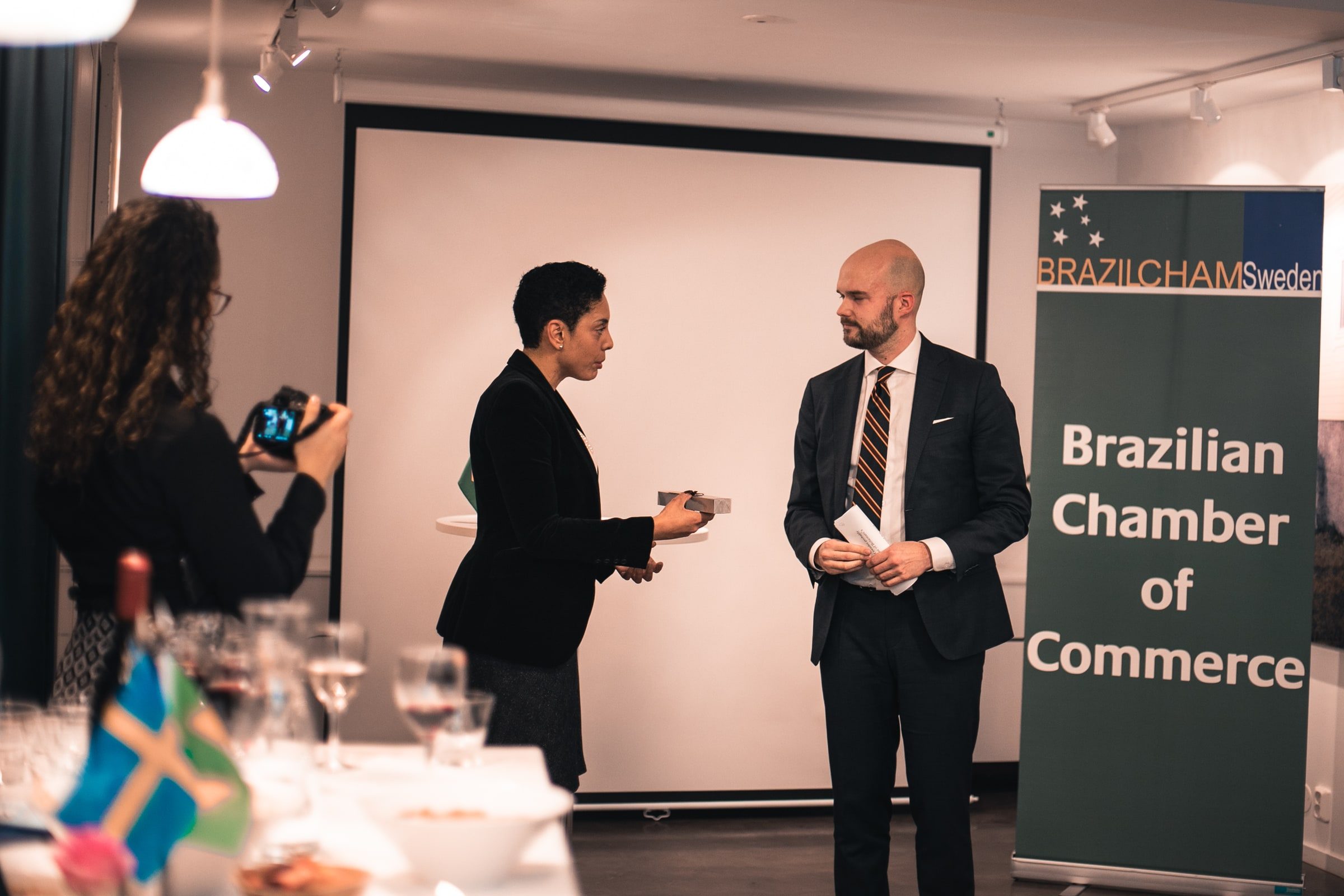 Formal presentation between two speakers at the front of the reception room.