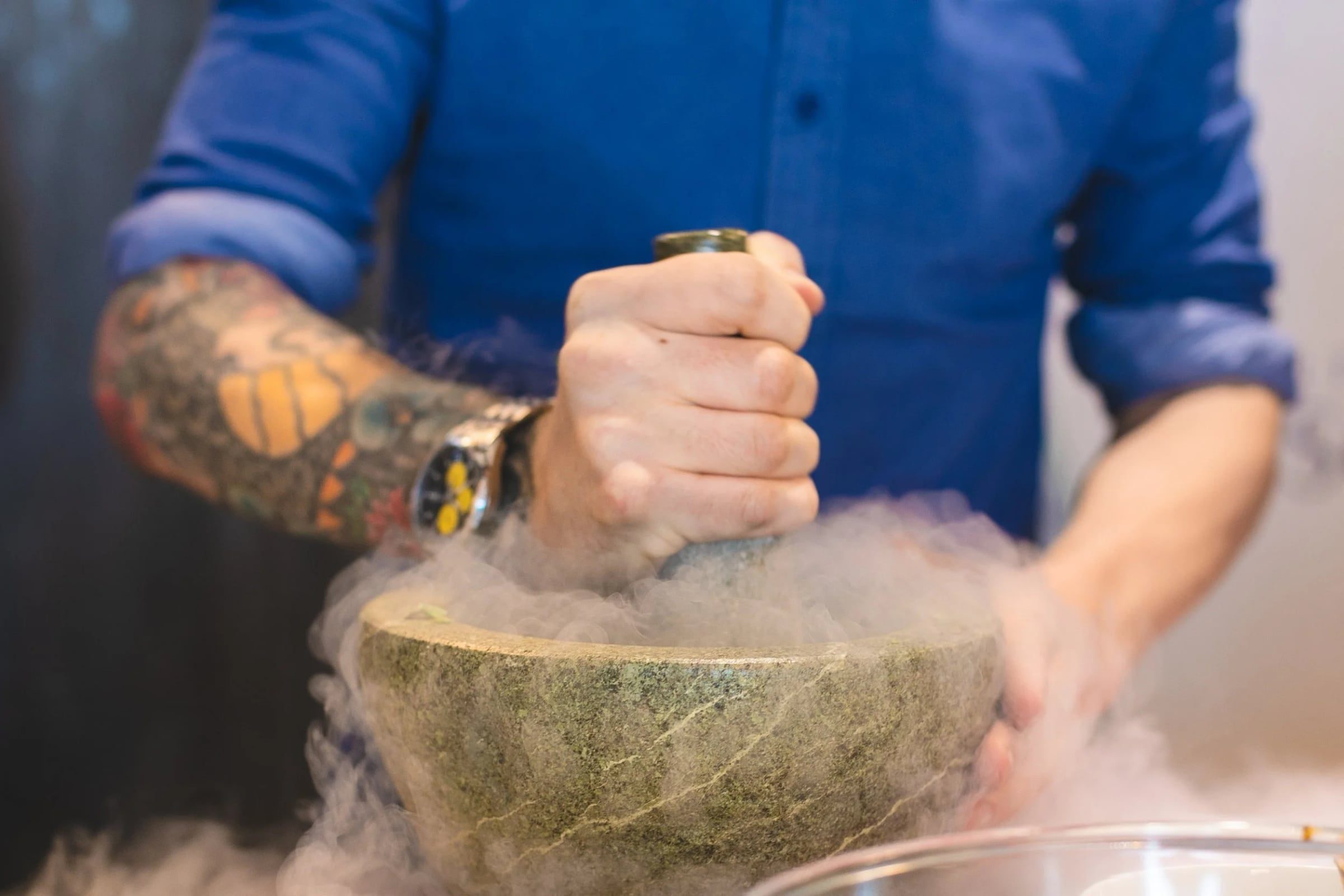 Hands grinding fresh ingredients in a stone mortar at the workshop