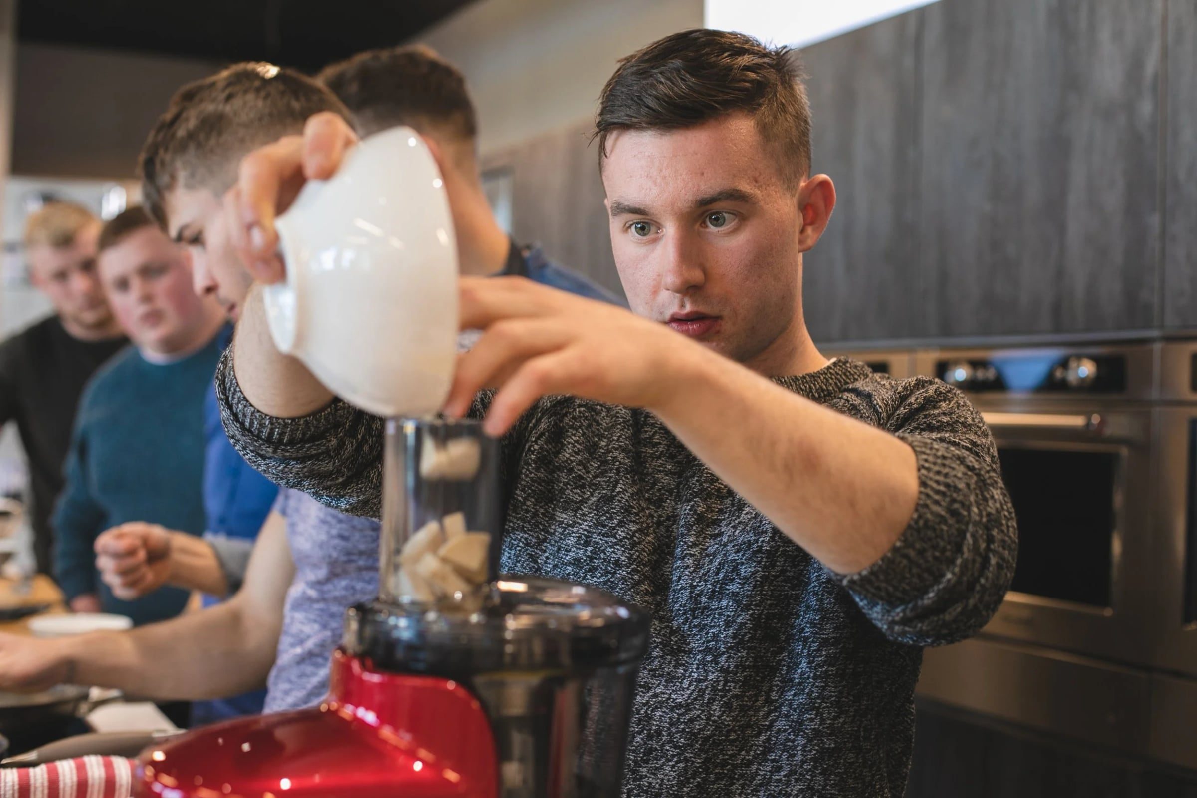 Participant adding ingredients to a red KitchenAid blender