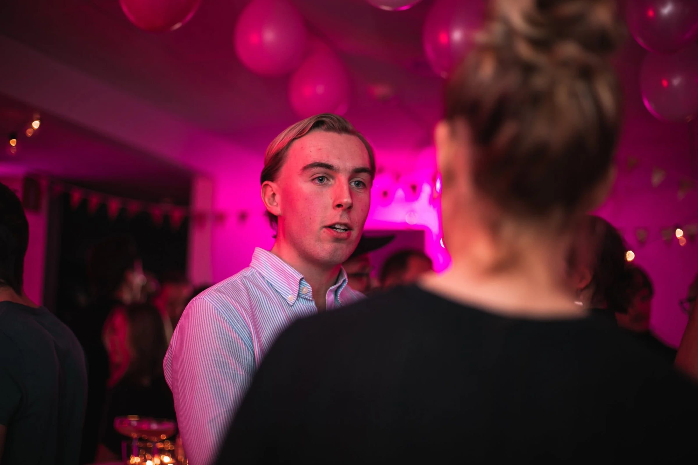 Guest speaking during a pink-lit corporate evening reception