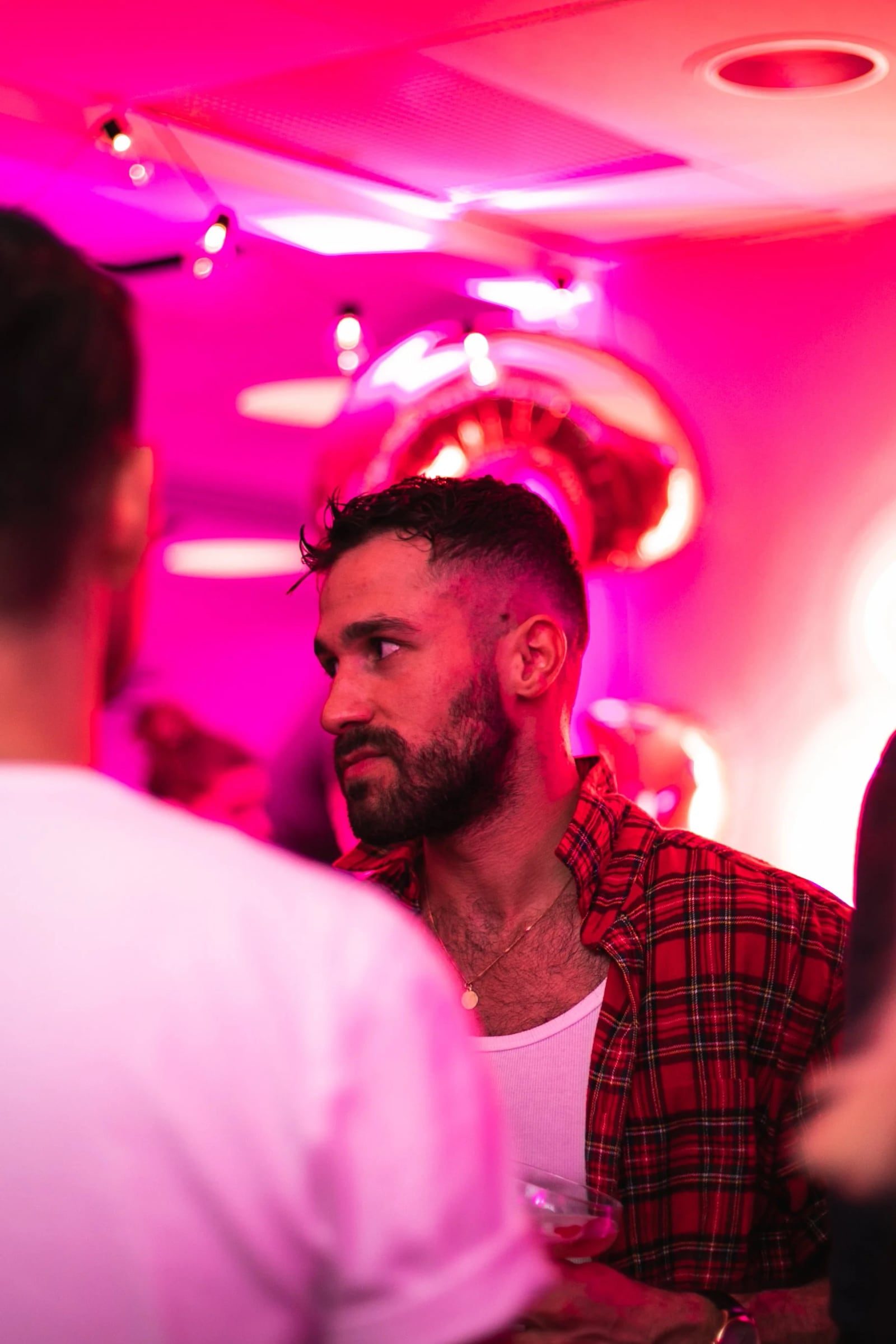 Bearded guest in conversation beneath neon reception lighting