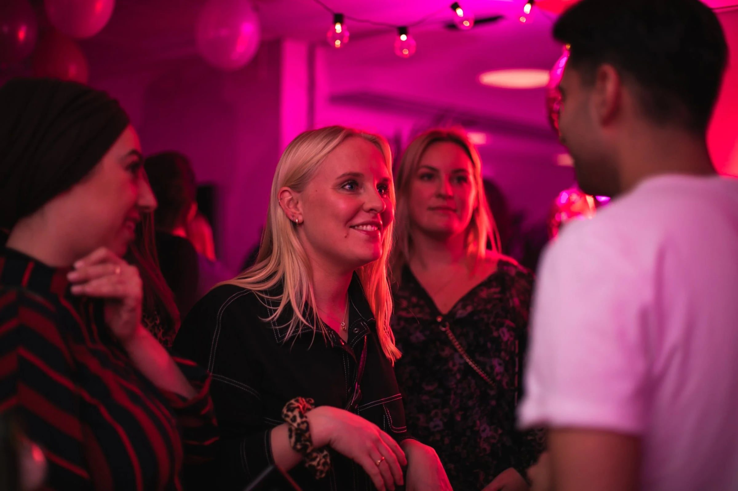 Guests networking over cocktails beneath saturated pink light