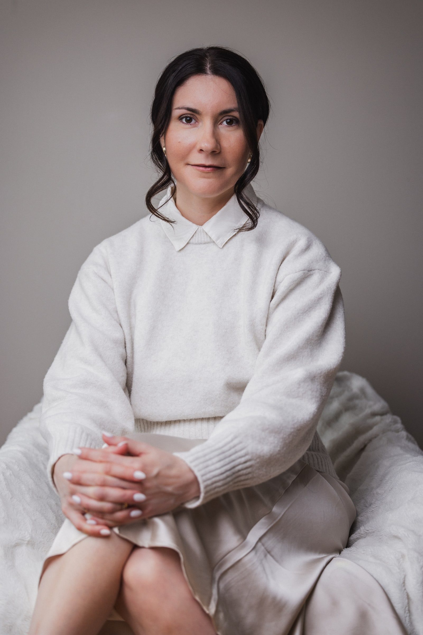 Seated professional portrait of a business coach against a neutral background.