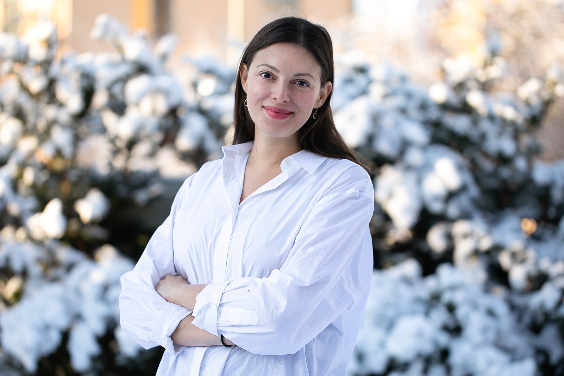 Outdoor team portrait of a woman in a white blouse with folded arms.