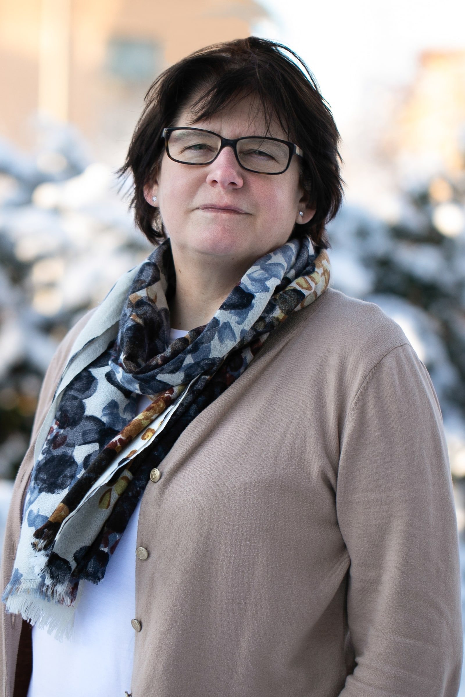 Close team portrait of a woman wearing glasses and a patterned scarf.