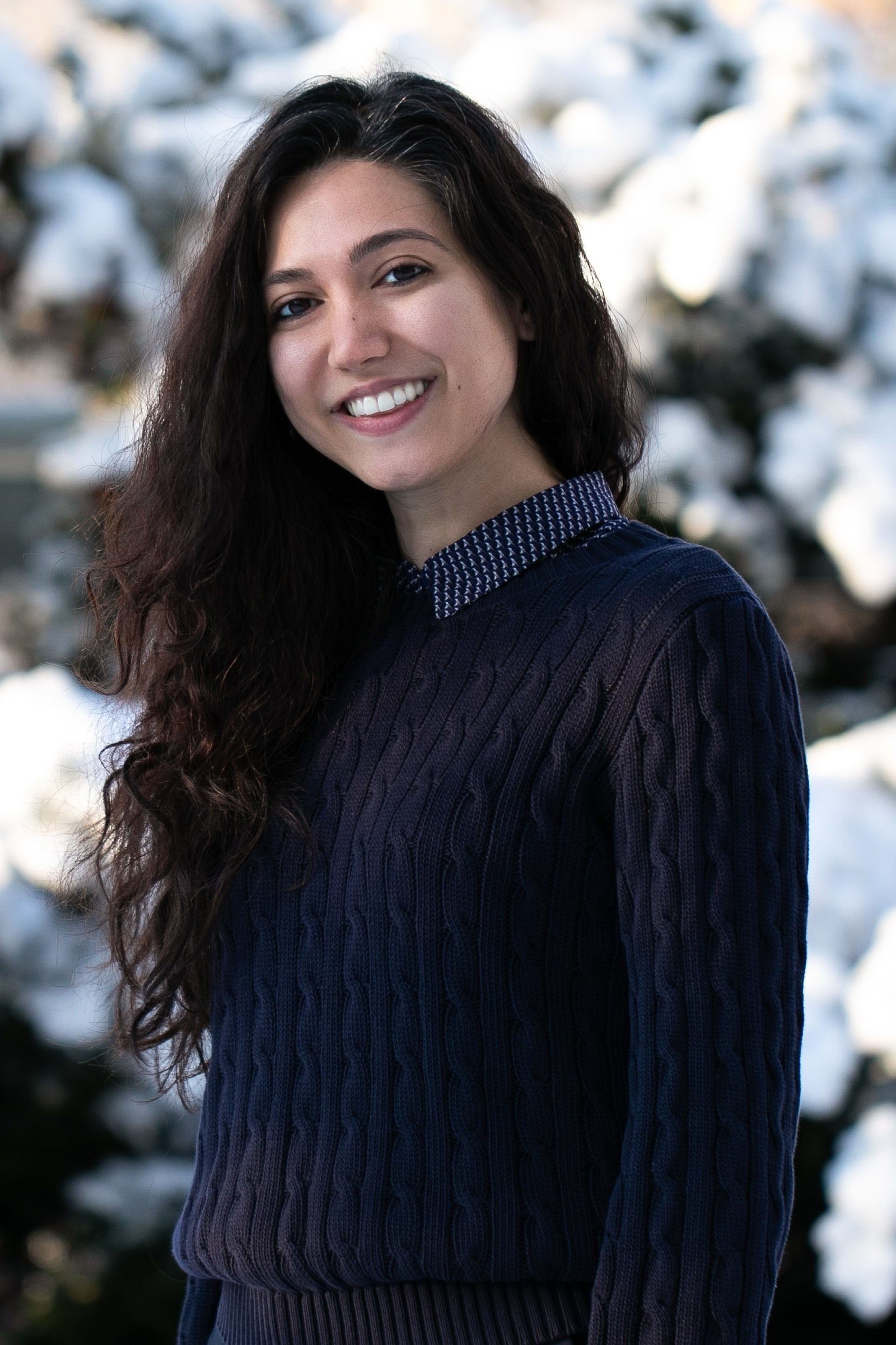 Smiling team member in a navy knit sweater photographed against a snowy background.