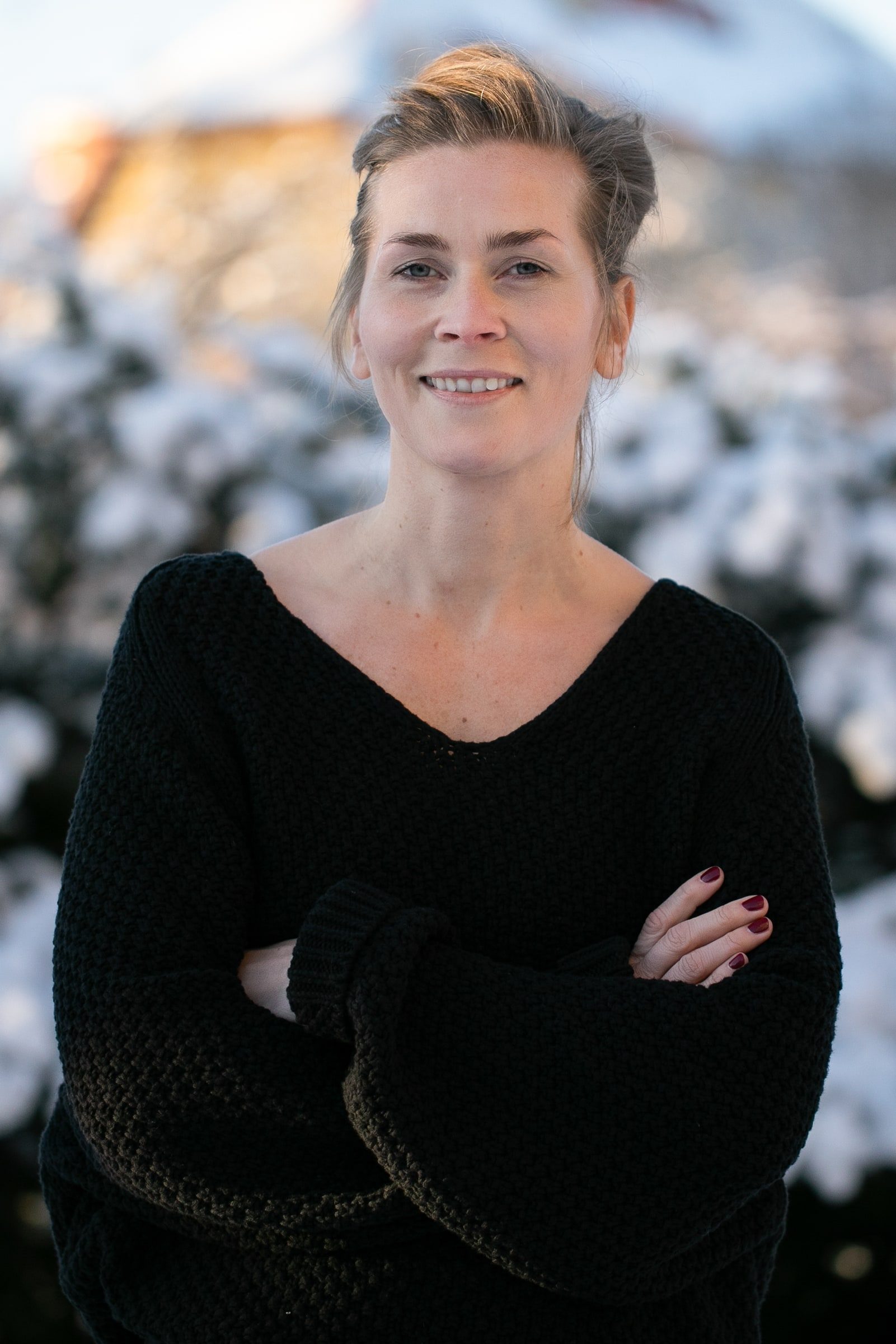 Close professional portrait of a woman with swept-back hair in a black top.