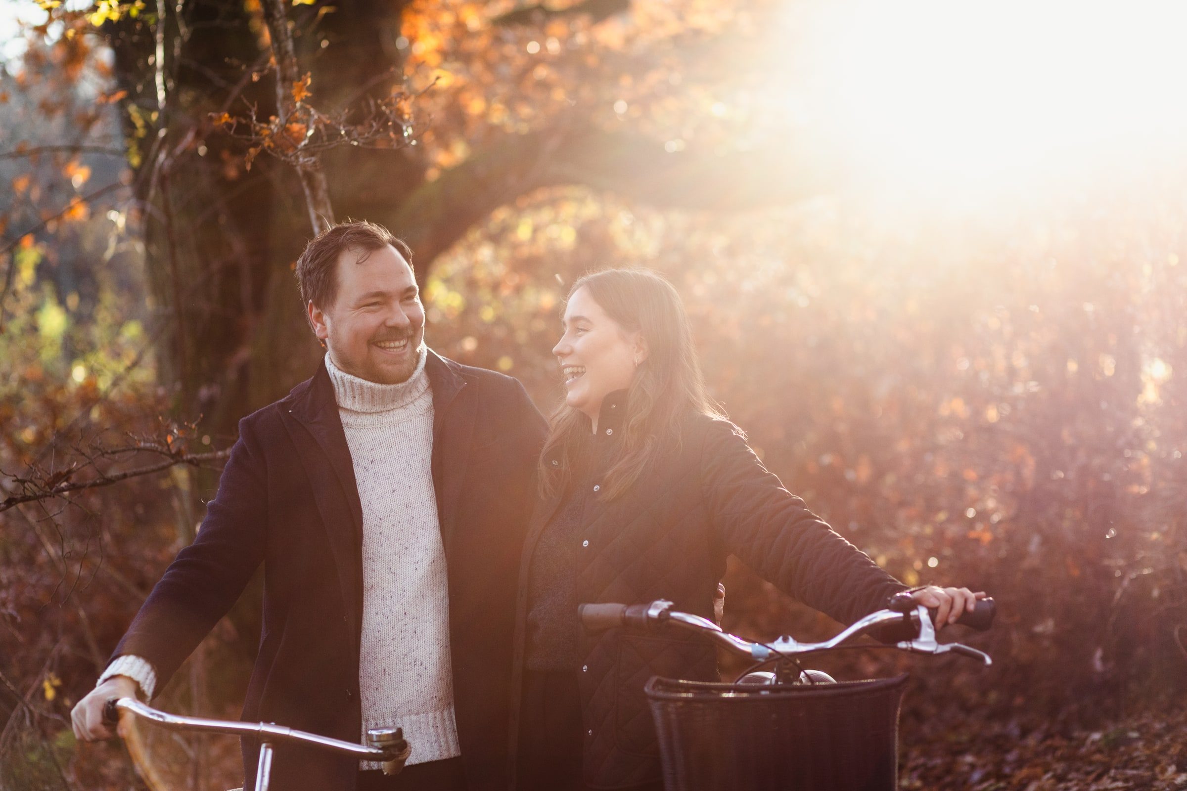 Couple walking with bicycles in warm golden-hour light.
