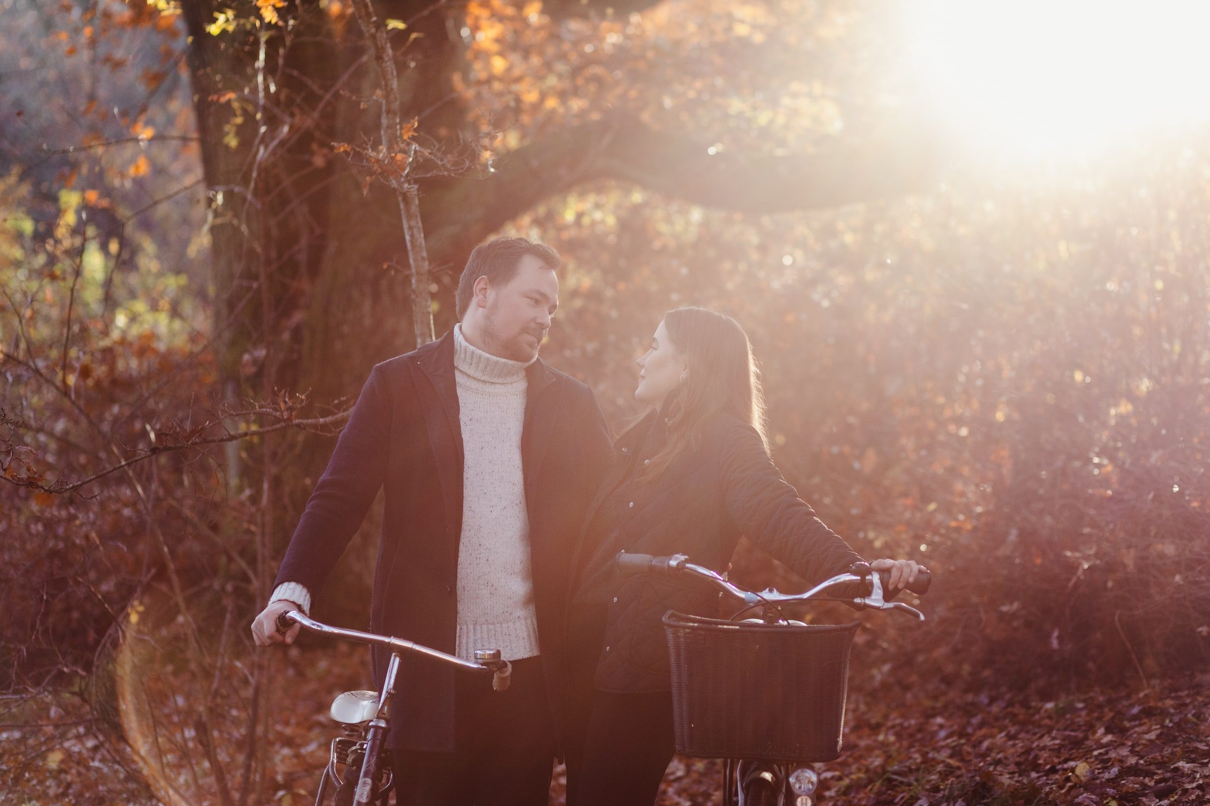 Couple pausing with bicycles on a woodland path.