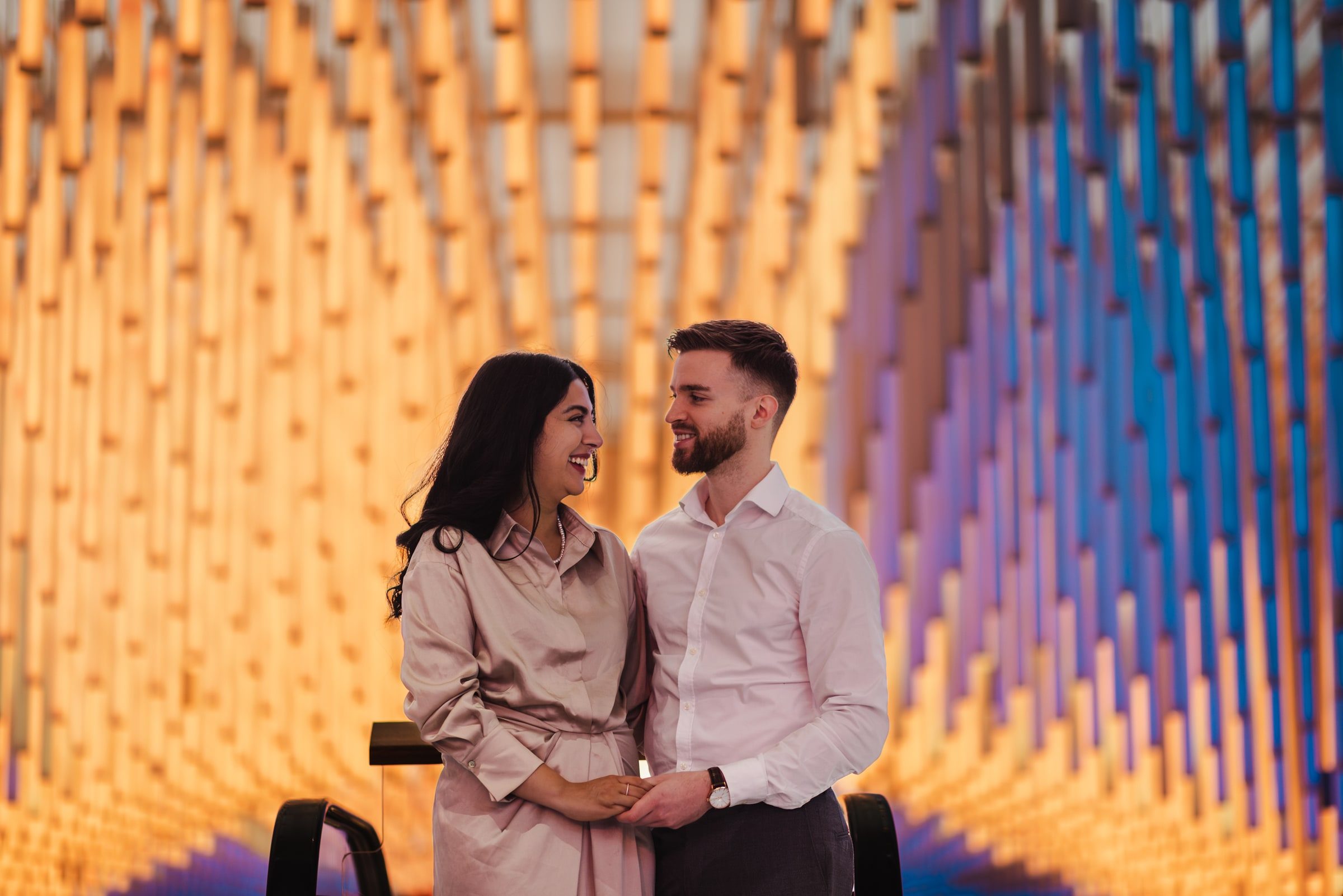Couple standing together in front of a colourful architectural wall.