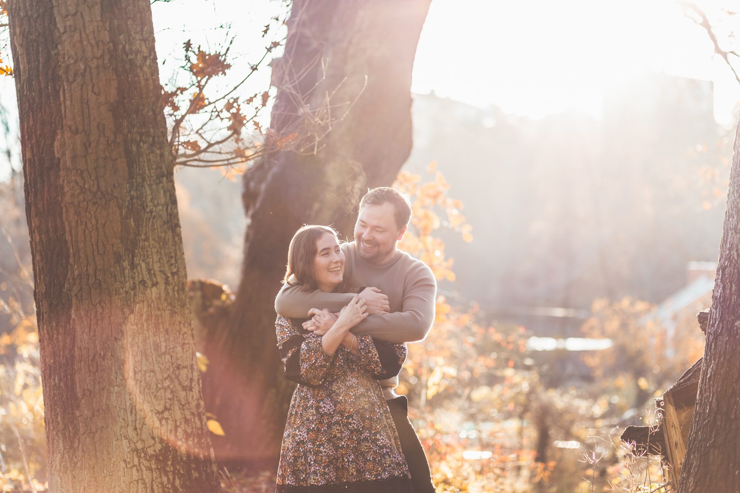 Couple embracing beside a tree in golden evening light.
