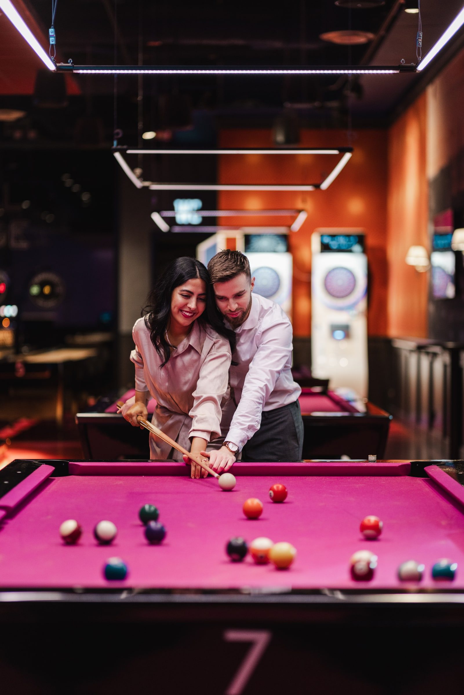 Couple playing pool together during an indoor portrait session.