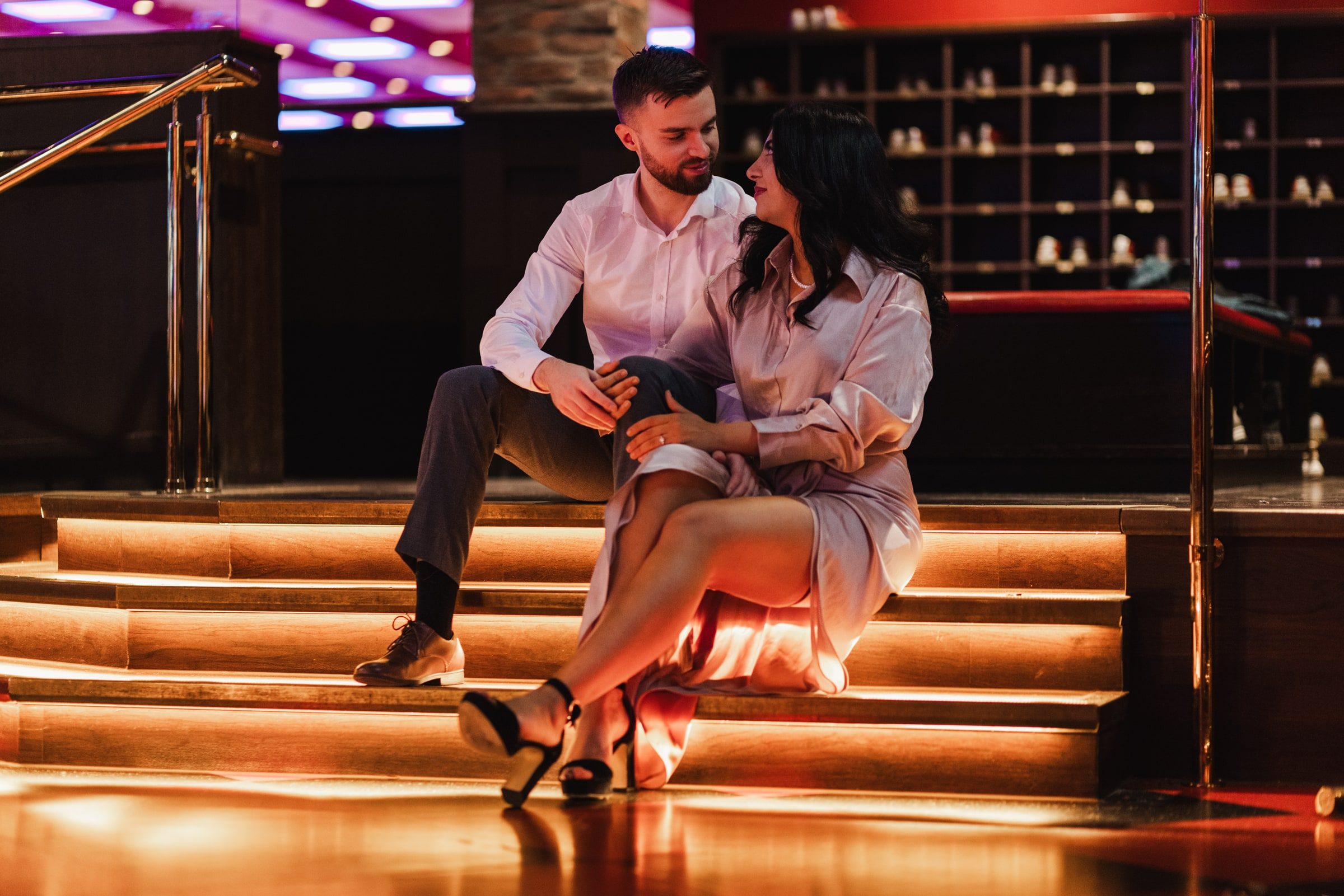 Couple seated together on illuminated venue steps.