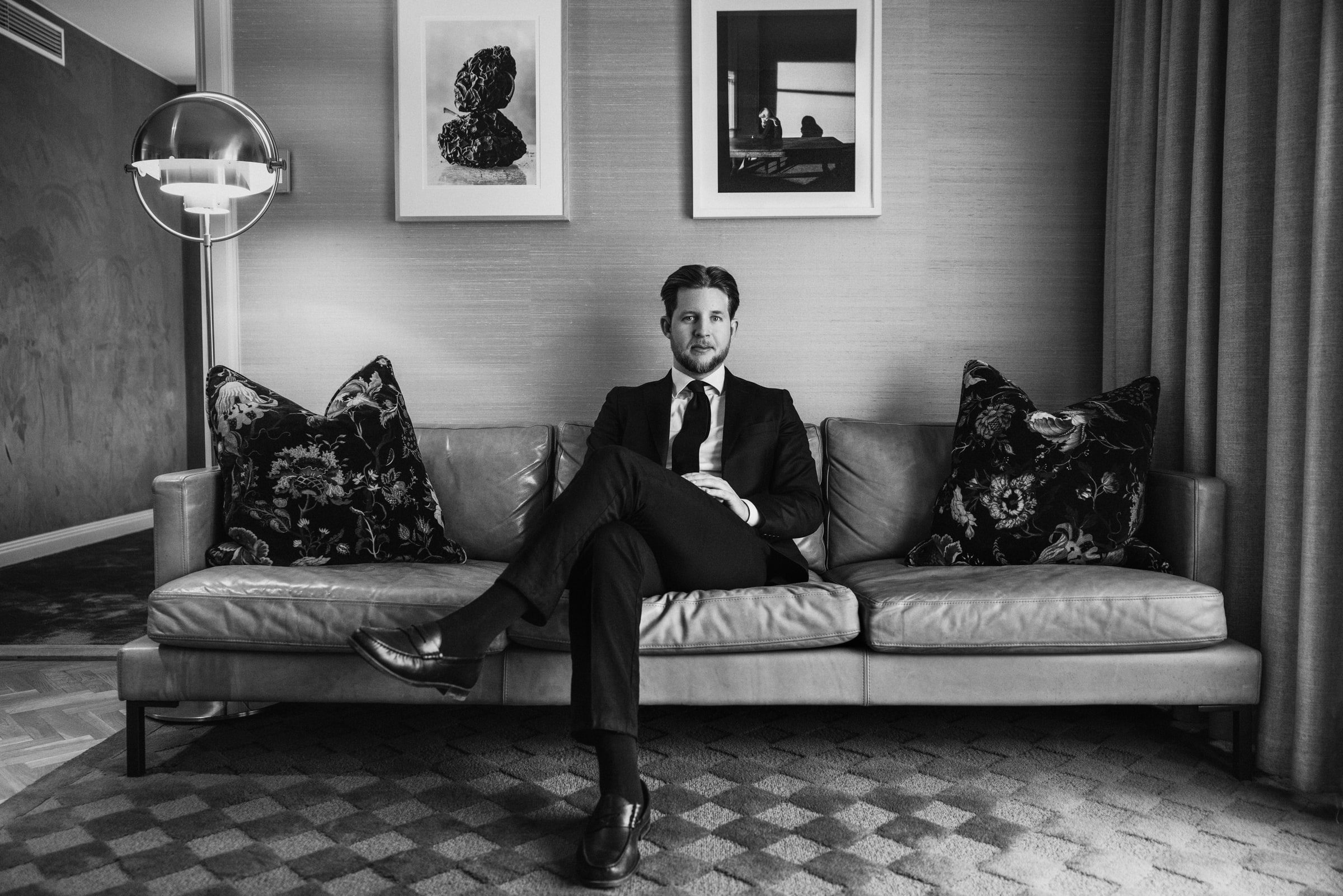 Black-and-white executive portrait of a concierge seated in a lounge.
