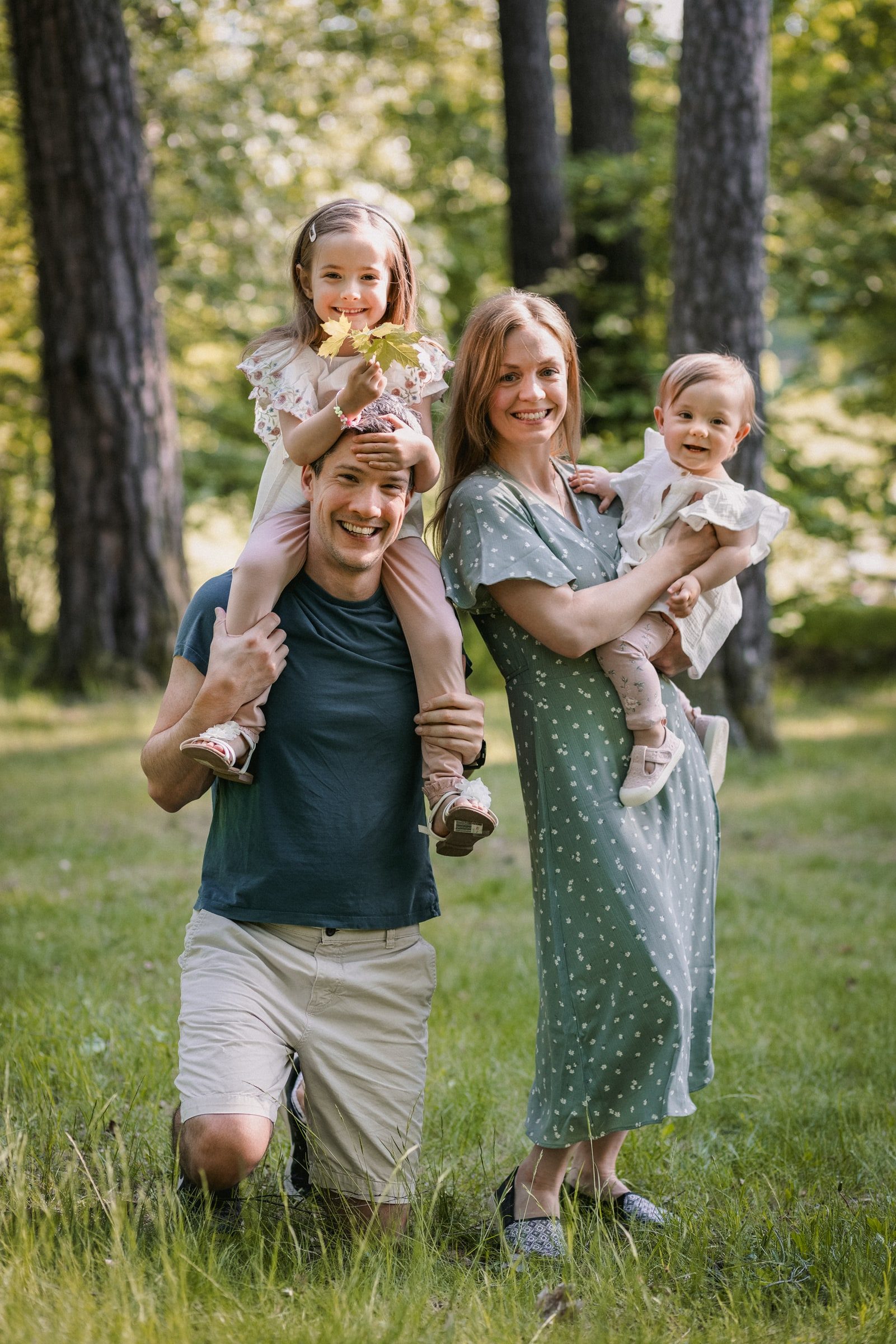 Parents carrying their two daughters during a playful summer family portrait.