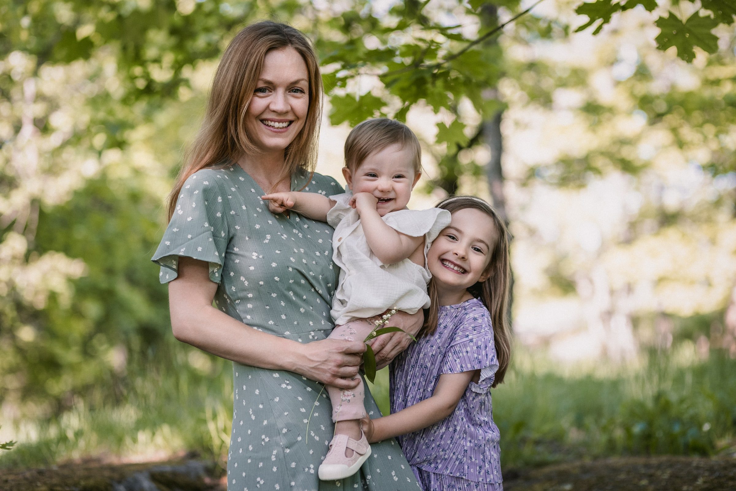 Mother holding her baby while the older sister leans in for a family portrait.