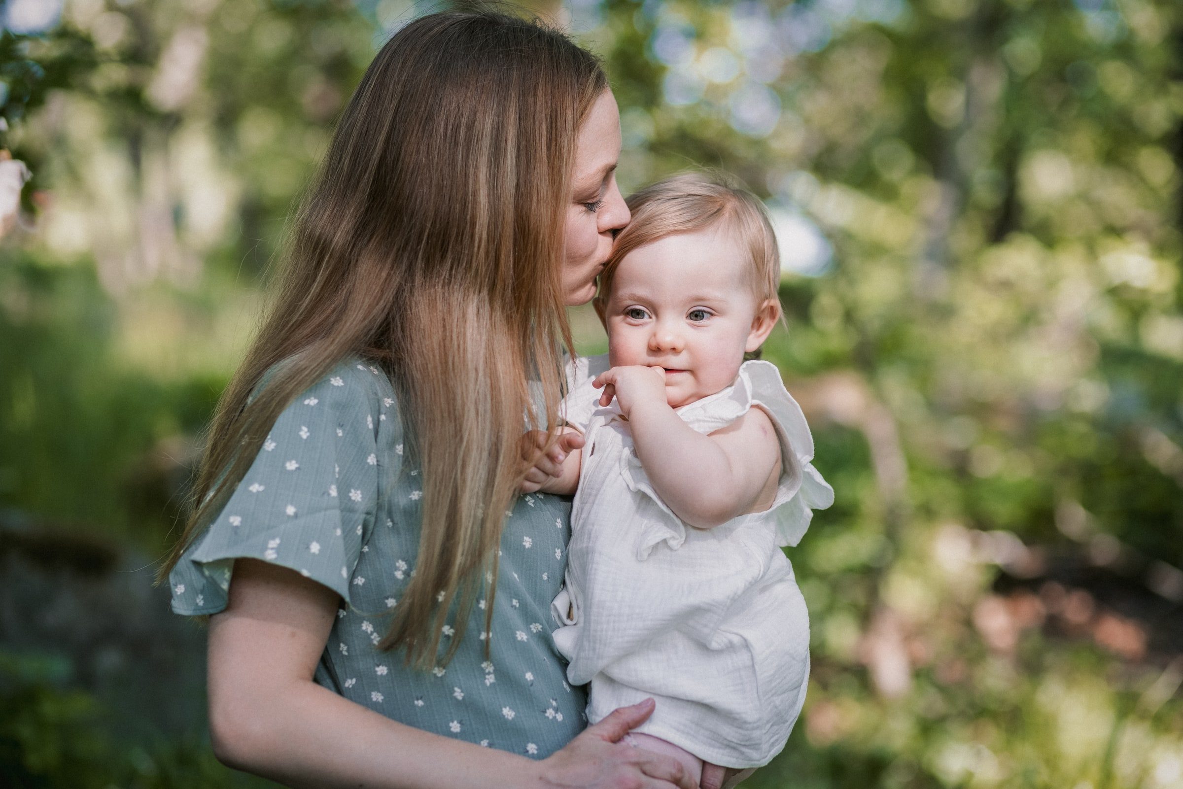 Mother kissing her baby during a close outdoor portrait.