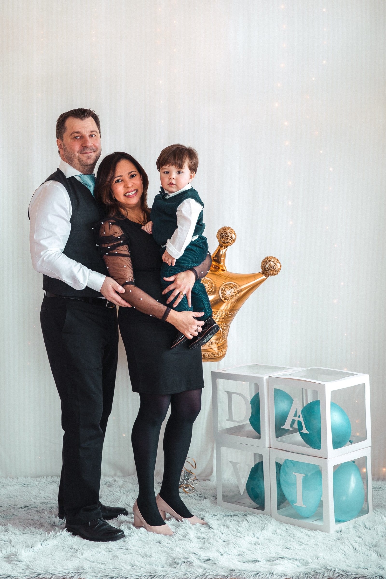 Parents holding their baby for a coordinated first-birthday family portrait.