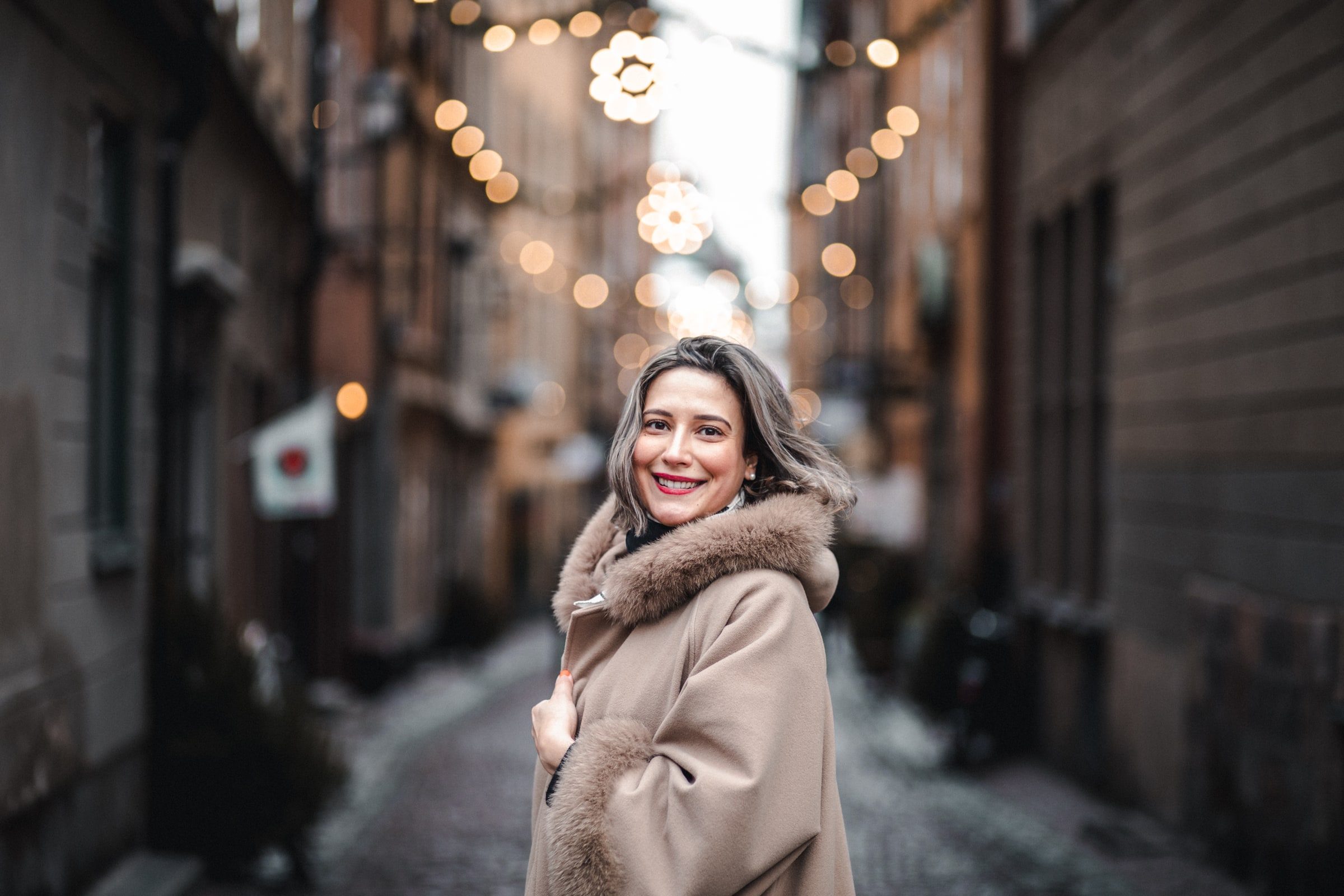 Woman smiling during a winter portrait session on a city street.