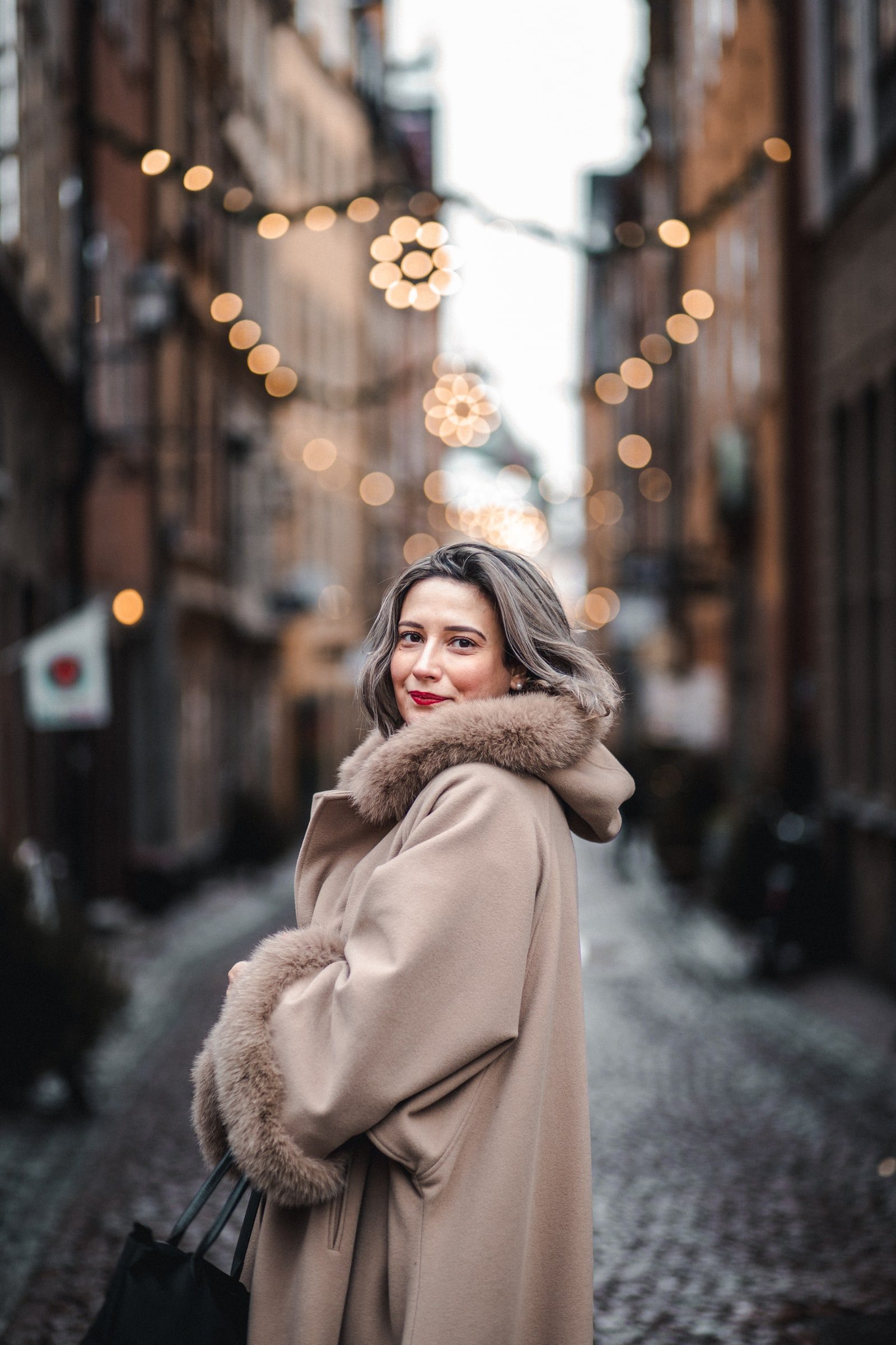 Close winter portrait framed by warm city lights.
