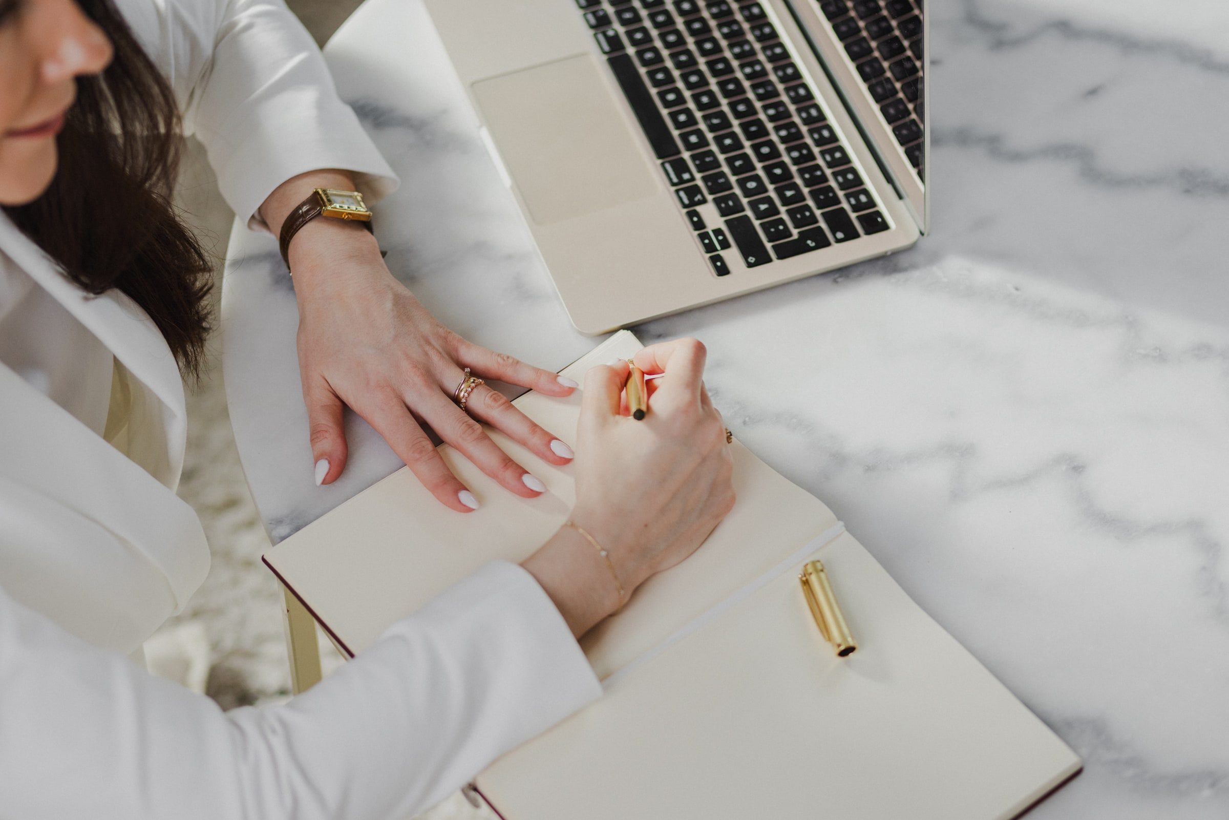 Business coach writing in a notebook at a bright marble desk.