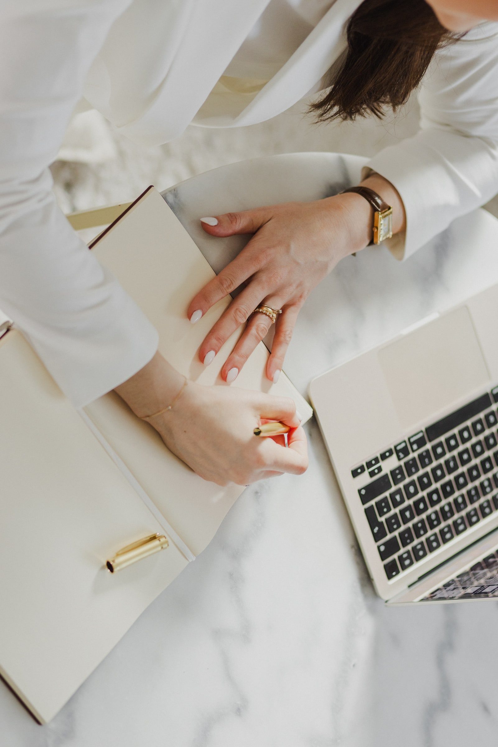 Hands writing notes beside a laptop during a business coaching session.