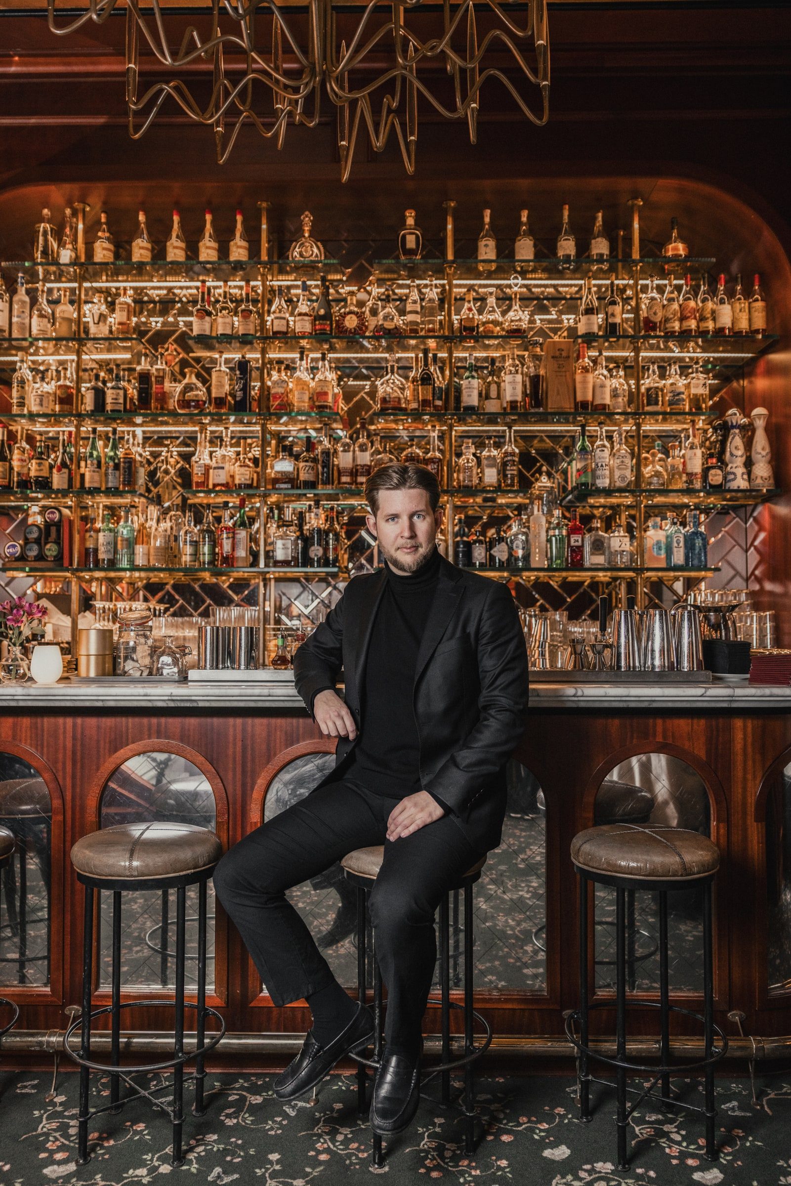 Personal branding portrait of a concierge seated at an ornate bar.