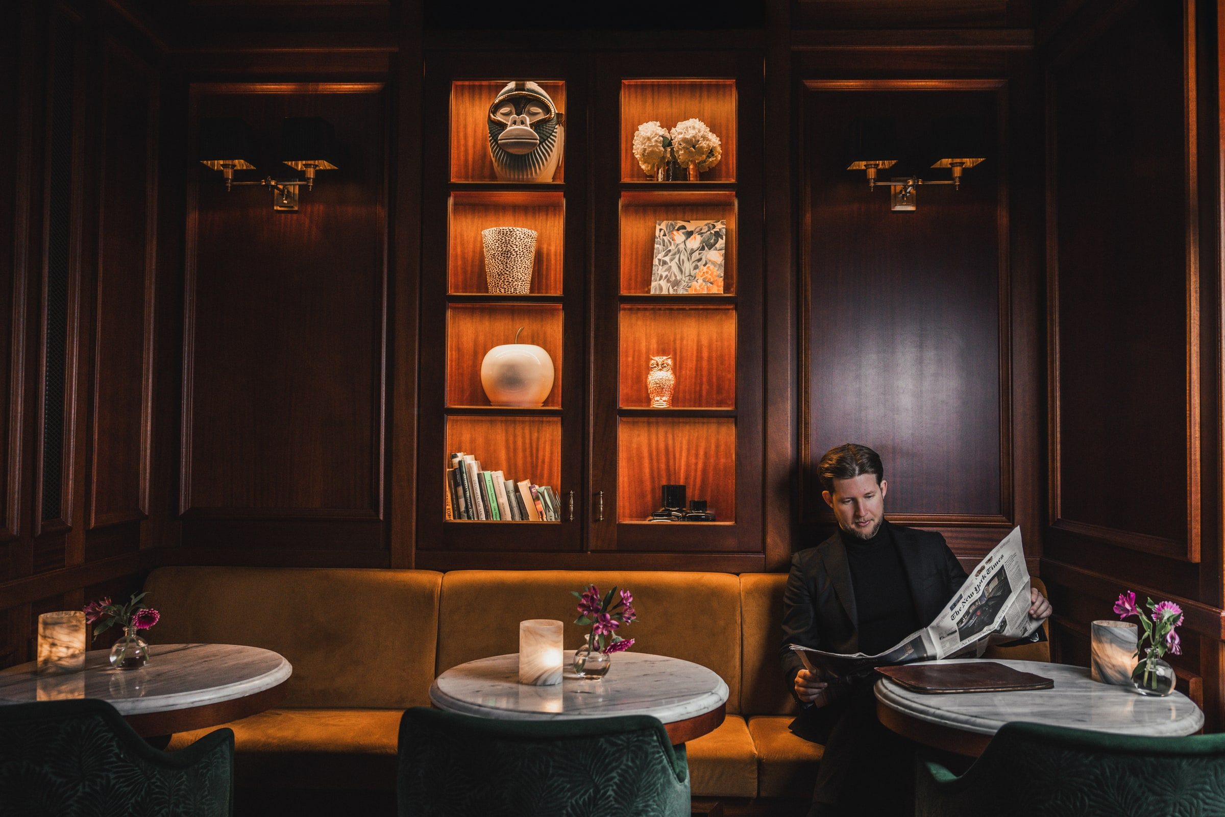 Concierge reading a newspaper in a refined hospitality interior.