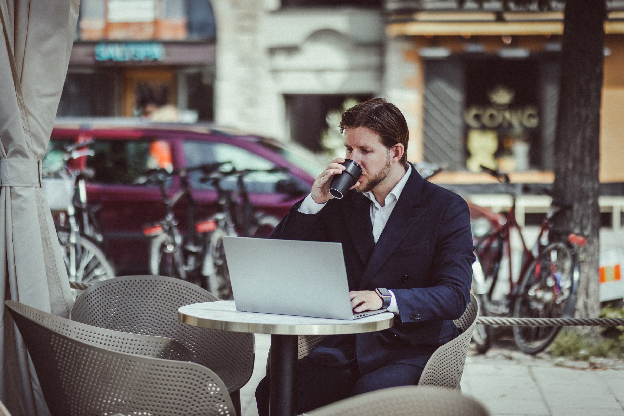 Concierge taking a call while working on a laptop at an outdoor café.