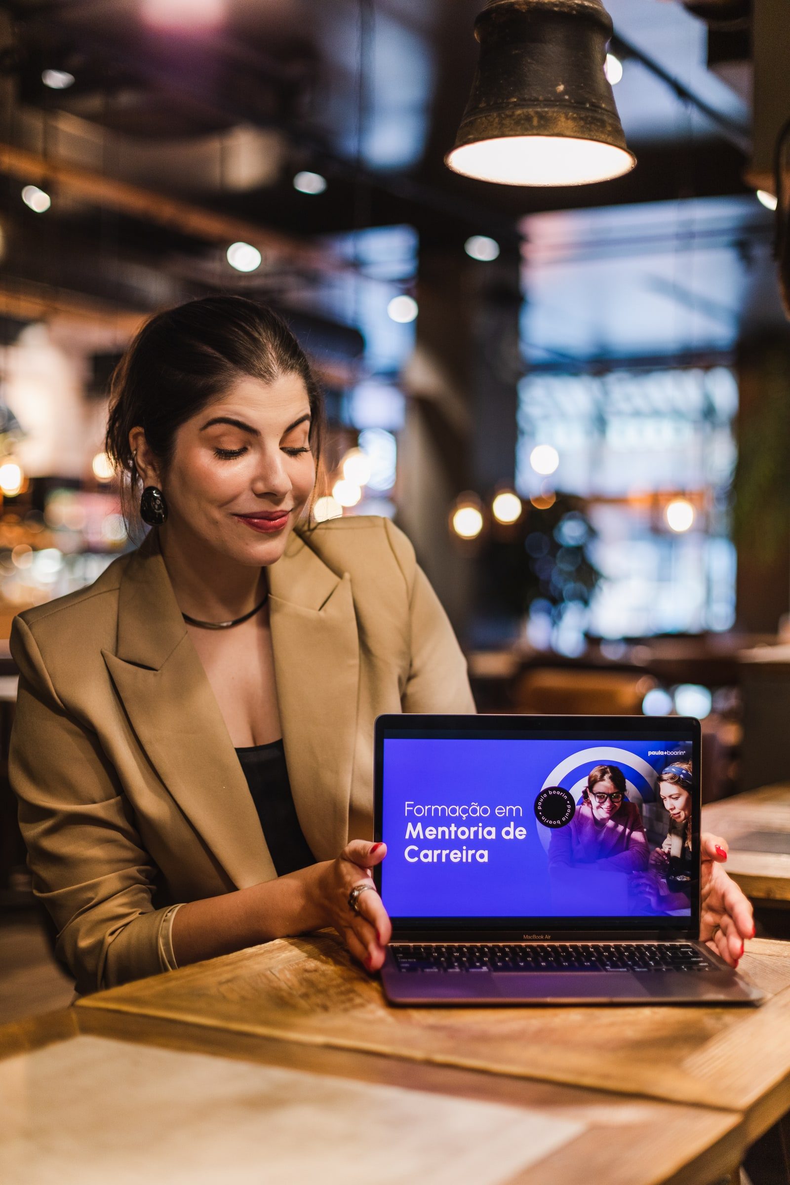 Editorial portrait of a writer seated with her laptop in a café.