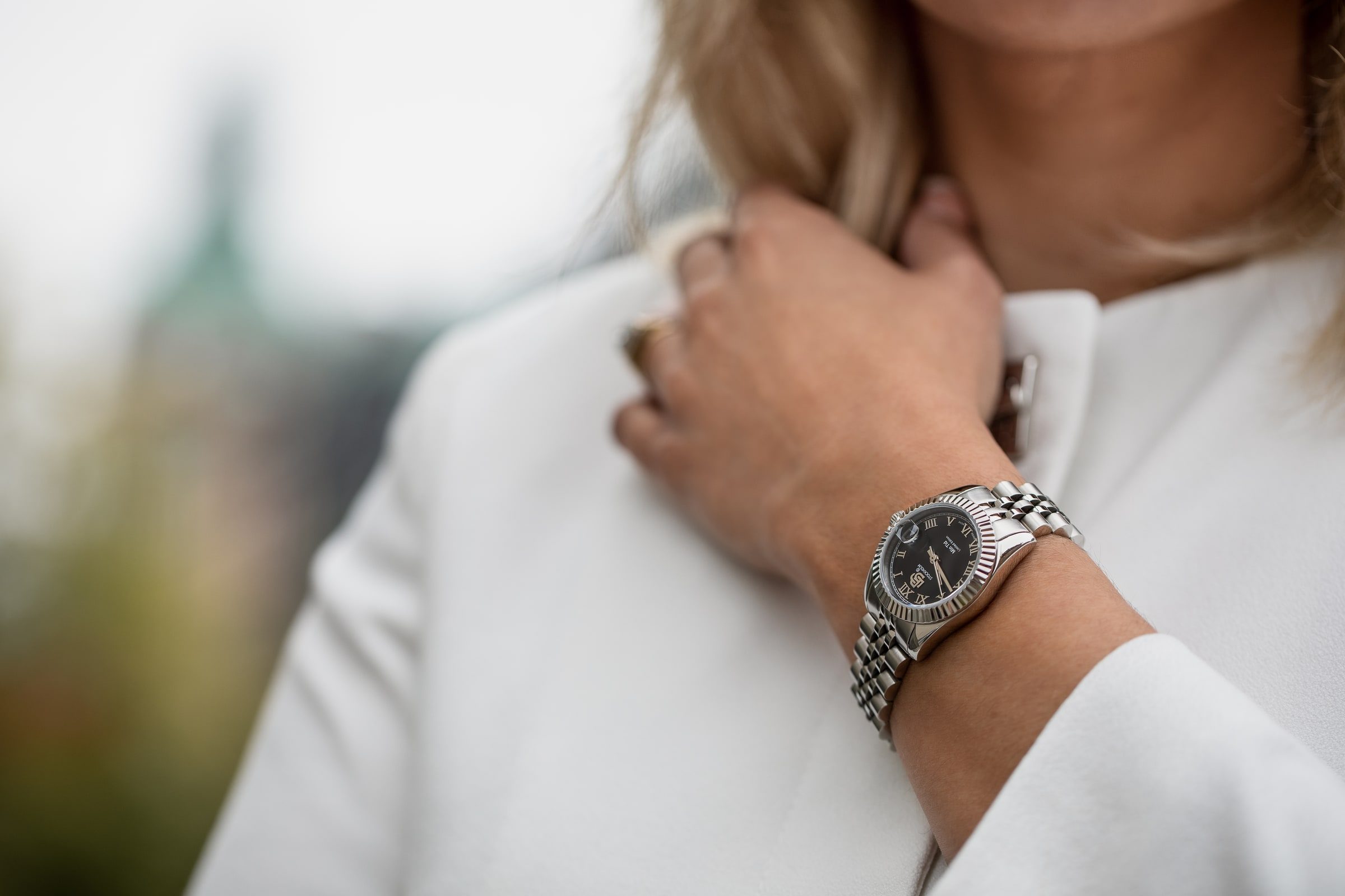 Close-up of a wristwatch styled with a white suit for a brand campaign.