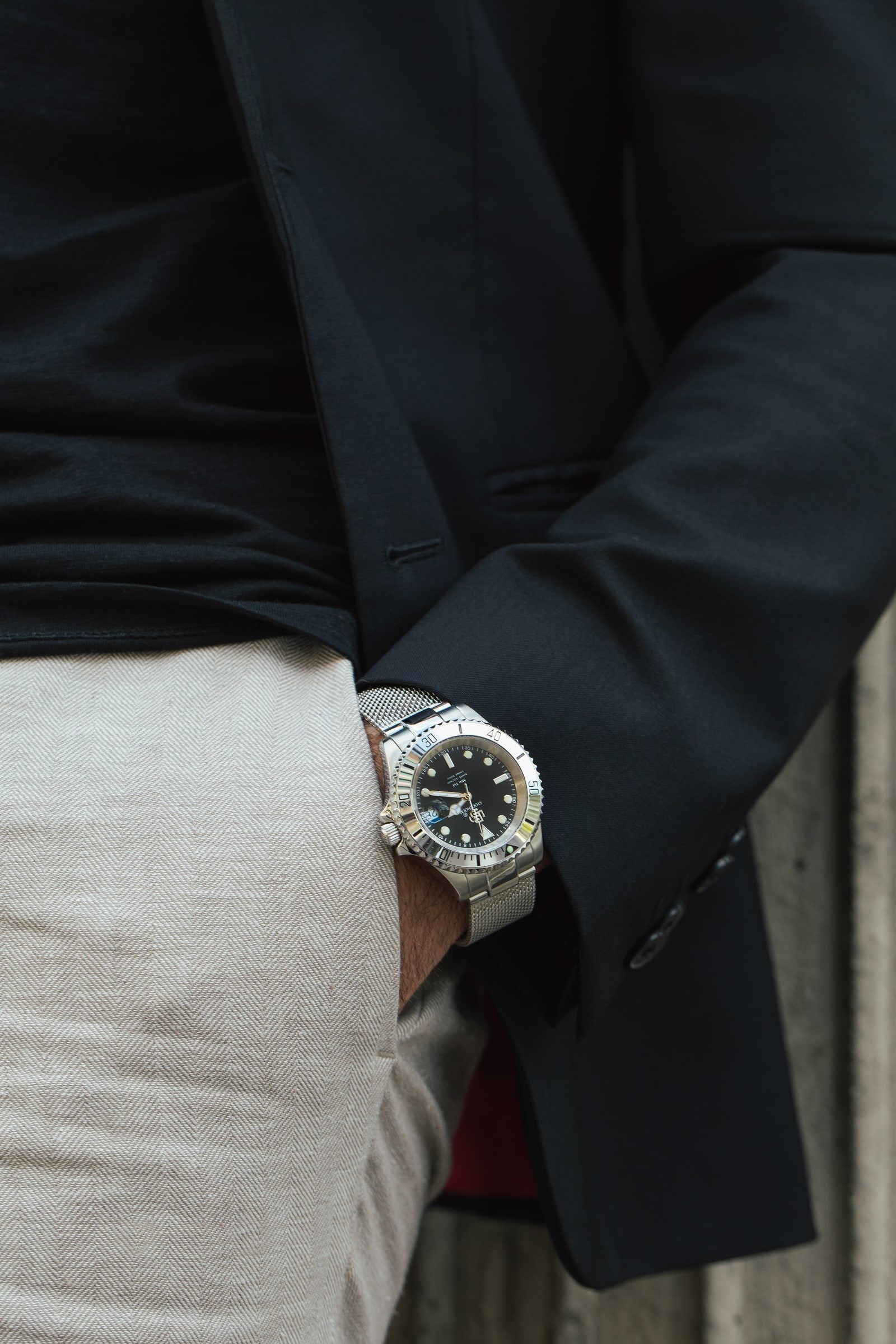 Close-up of a steel wristwatch styled with a light grey suit.
