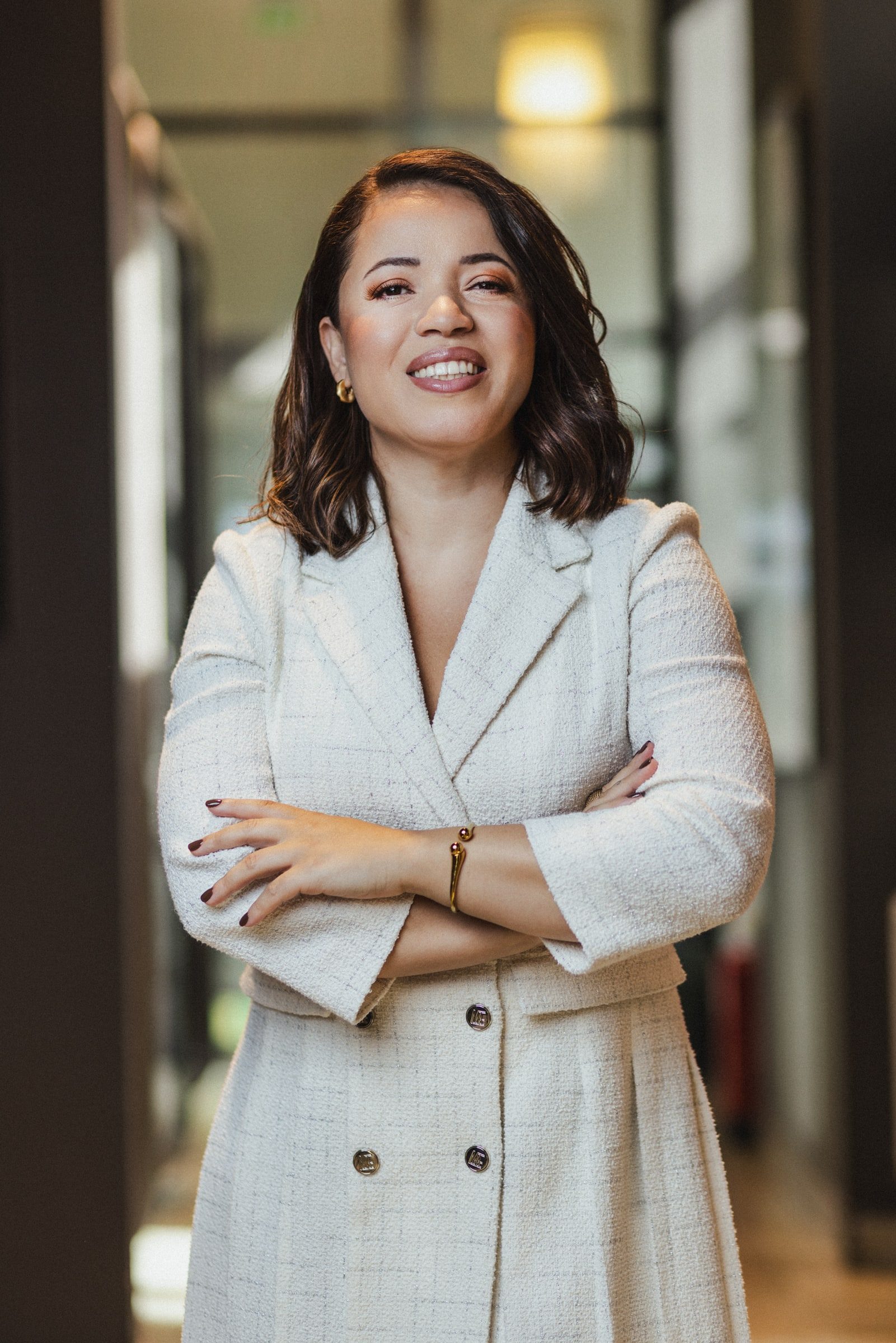 Professional portrait of a woman smiling in a softly lit interior.